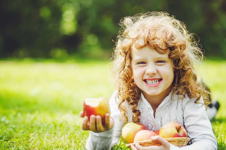 Little girl eating apple and showing her white teeth's